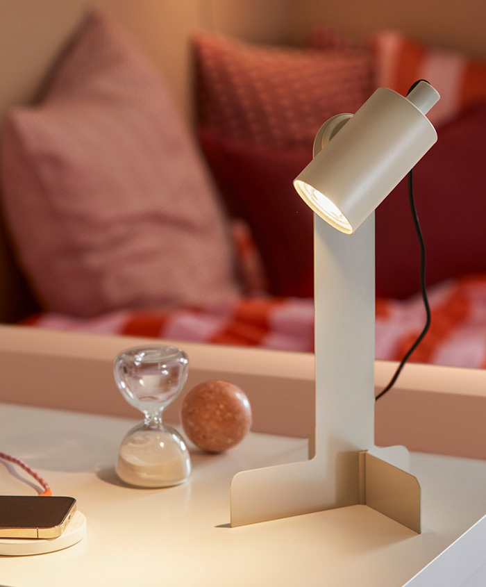 Beige lamp on white desk. Hourglass, round object. Pink lights, calm atmosphere.