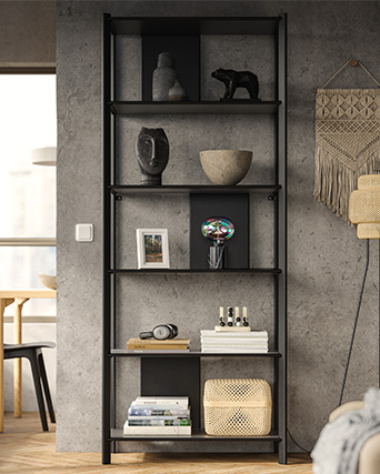 Estantería negra con objetos decorativos sobre pared gris de estilo industrial.