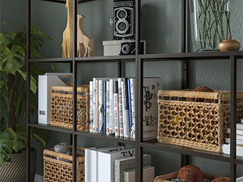 A dark metal bookshelf holds books, wicker baskets, decorative giraffes, a vintage camera, and a plant, creating a cozy display.