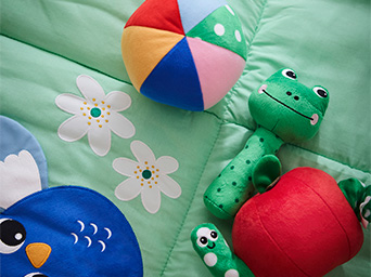 Varios peluches de animalitos sobre una colcha de bebé.