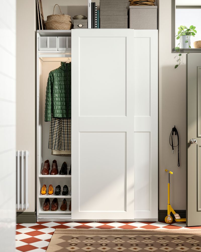  Organized white wardrobe with sliding doors, shoes, clothes, and storage boxes.