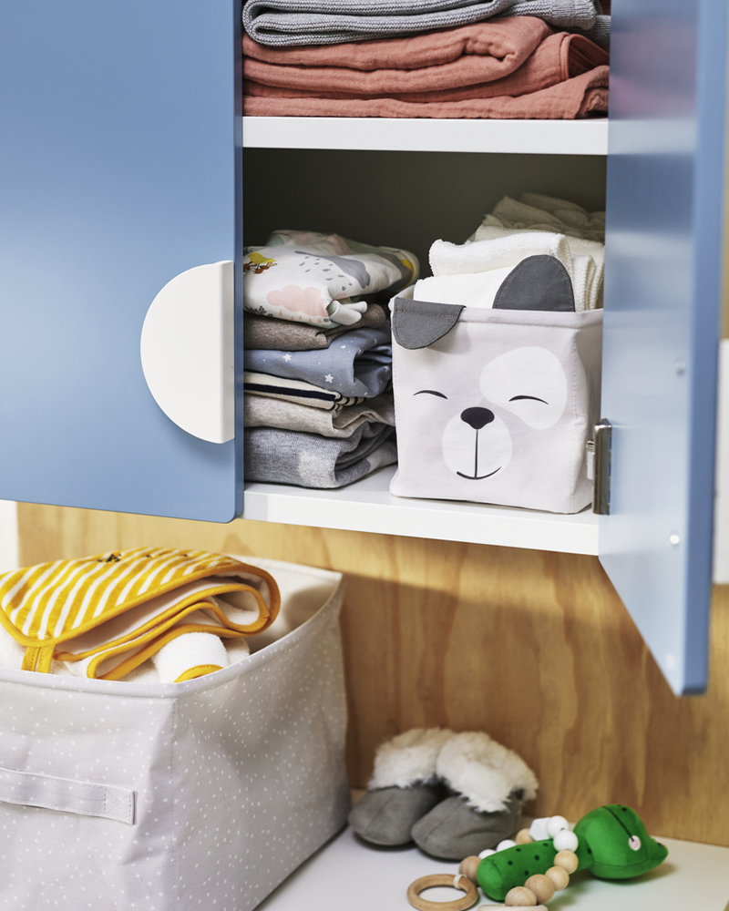 A light blue DRÖMSLOTT box set of 2, neatly placed on a shelf containing folded clothes and soft toys.