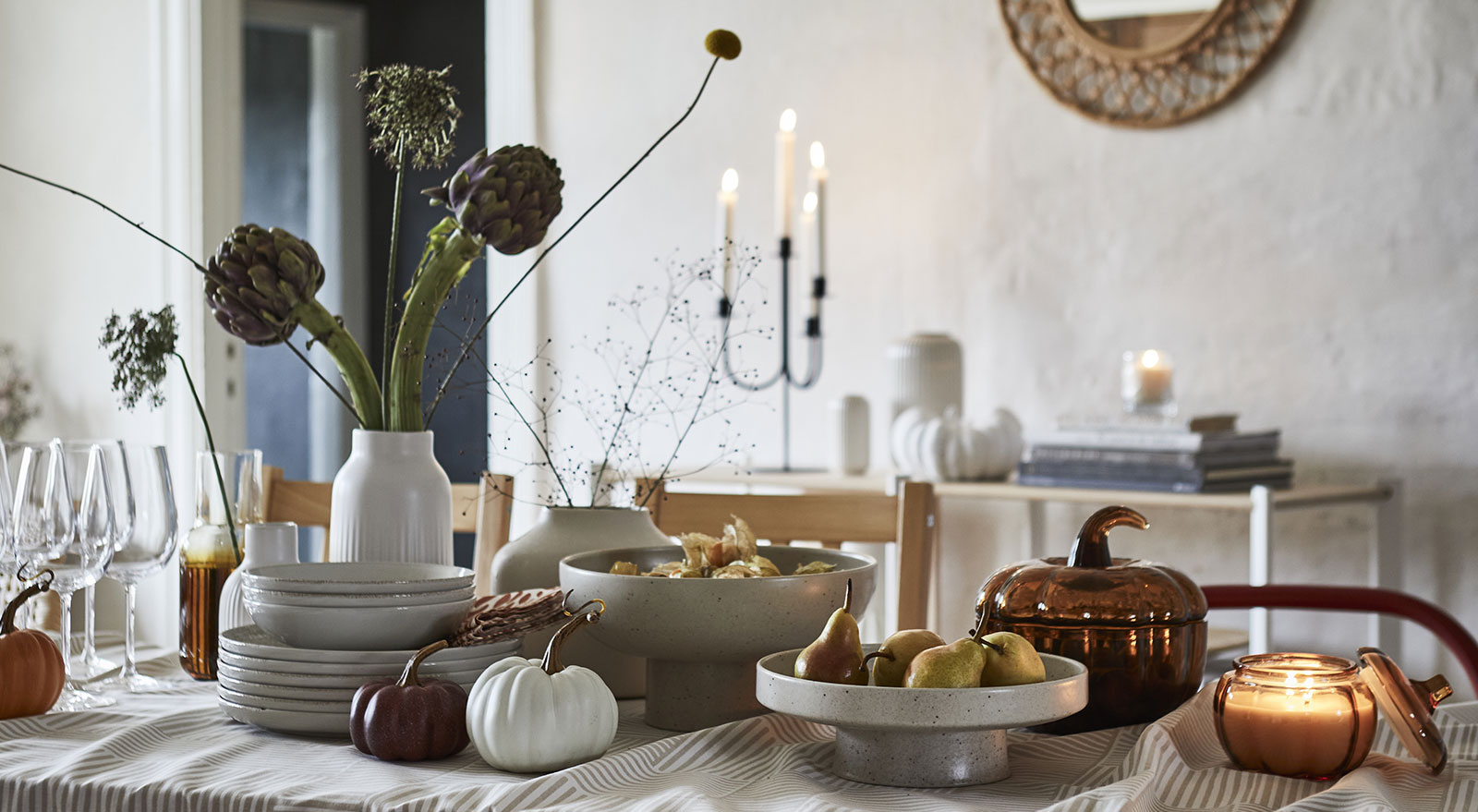 A light beige HÖSTAGILLE serving stand and bowl showcase fruit on a beautifully set dining table.