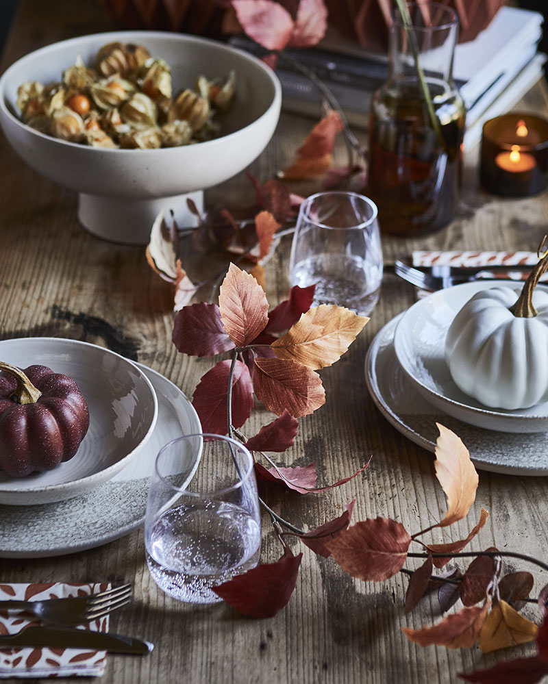 A dining table adorned with a HÖSTAGILLE artifi cial garland in mixed colours, surrounded by elegant dishes and glassware