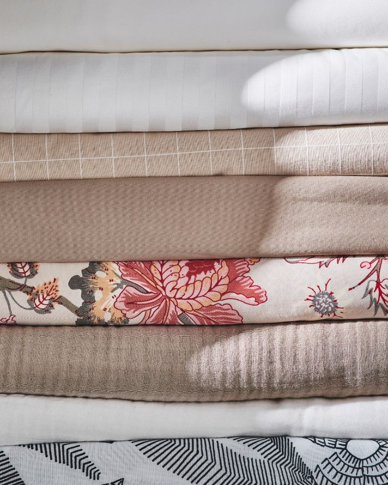 A pile of eight different types of bed linen including white NATTJASMIN and black and white BROKDRACENA bed linen.