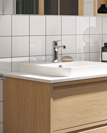 Lavabo blanco con grifo cromado sobre mueble de madera y pared azulejada.