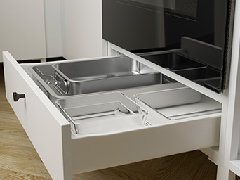 Cajón blanco inferior abierto con recipientes de cristal y bandeja metálica de horno.