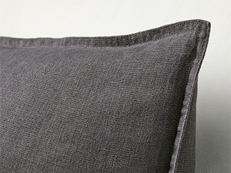 Primer plano de una almohada decorativa gris oscuro con borde cosido, mostrando la textura de la tela para añadir confort y estilo.