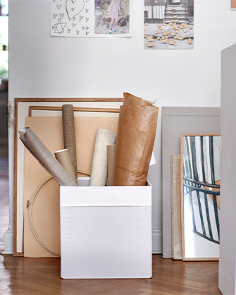Two-tone storage bin in white, holding rolls of paper and prints. Practical solution for artists and crafts in a studio or workshop.