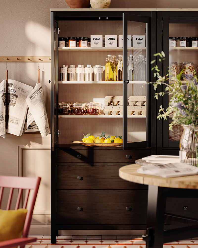 Jars and bottles are on display in a black-brown HEMNES glass-door cabinet with three drawers in a classic-styled reception.