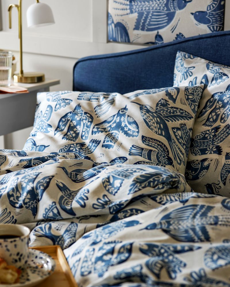 A BITTERSÖTA duvet cover and pillowcase set displayed on a bed with a matching pattern, paired with a bedside table.