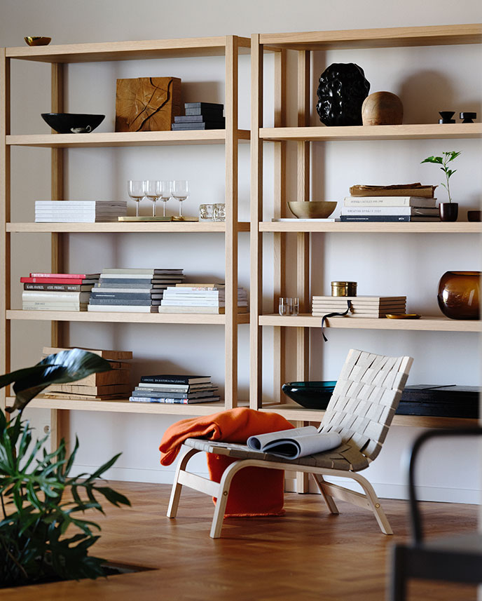 An airy, bright living room with side-by-side STOCKHOLM 2025 shelving units displaying books and decorative items.