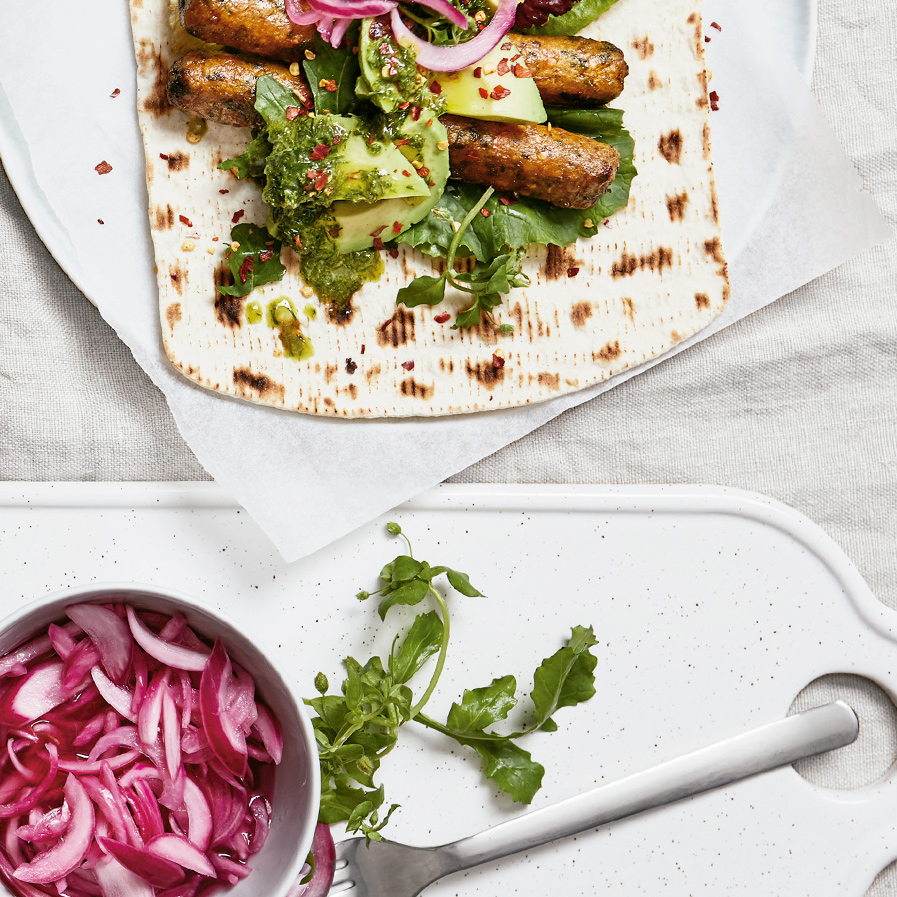 Vegetable hot dogs with avocado, herb salsa, pickled red onion and chili flakes