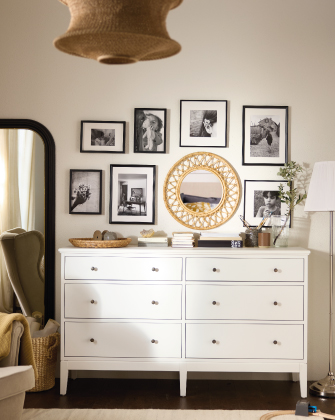 Cómoda blanca con espejo y cuadros decorativos.