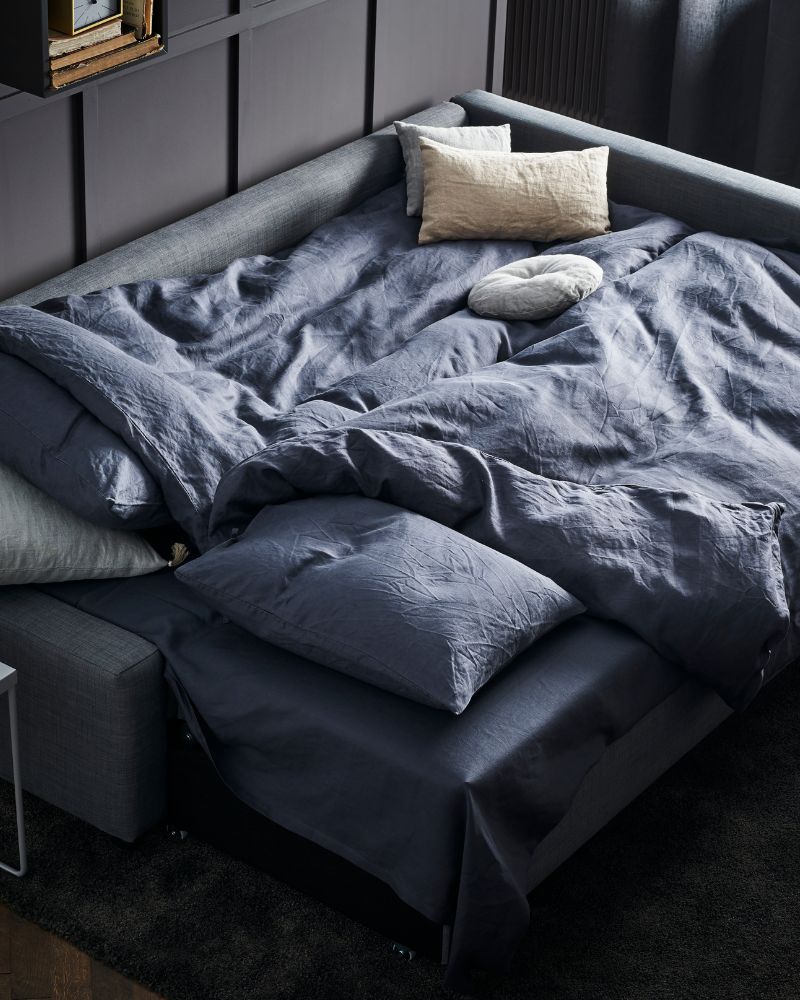 Modern living room with FRIHETEN sofa bed, STOENSE rug, ÄNGSLILJA duvet set and LENDA curtains.