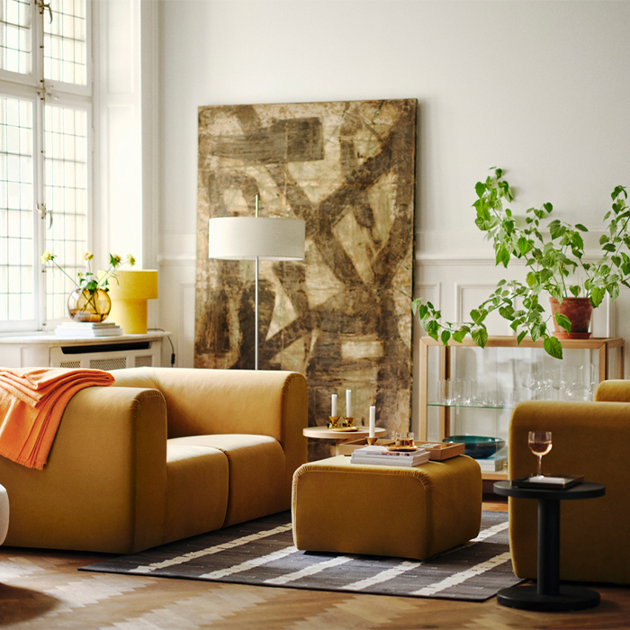 Sala elegante con sillones de terciopelo mostaza, un cuadro abstracto grande y plantas de interior.