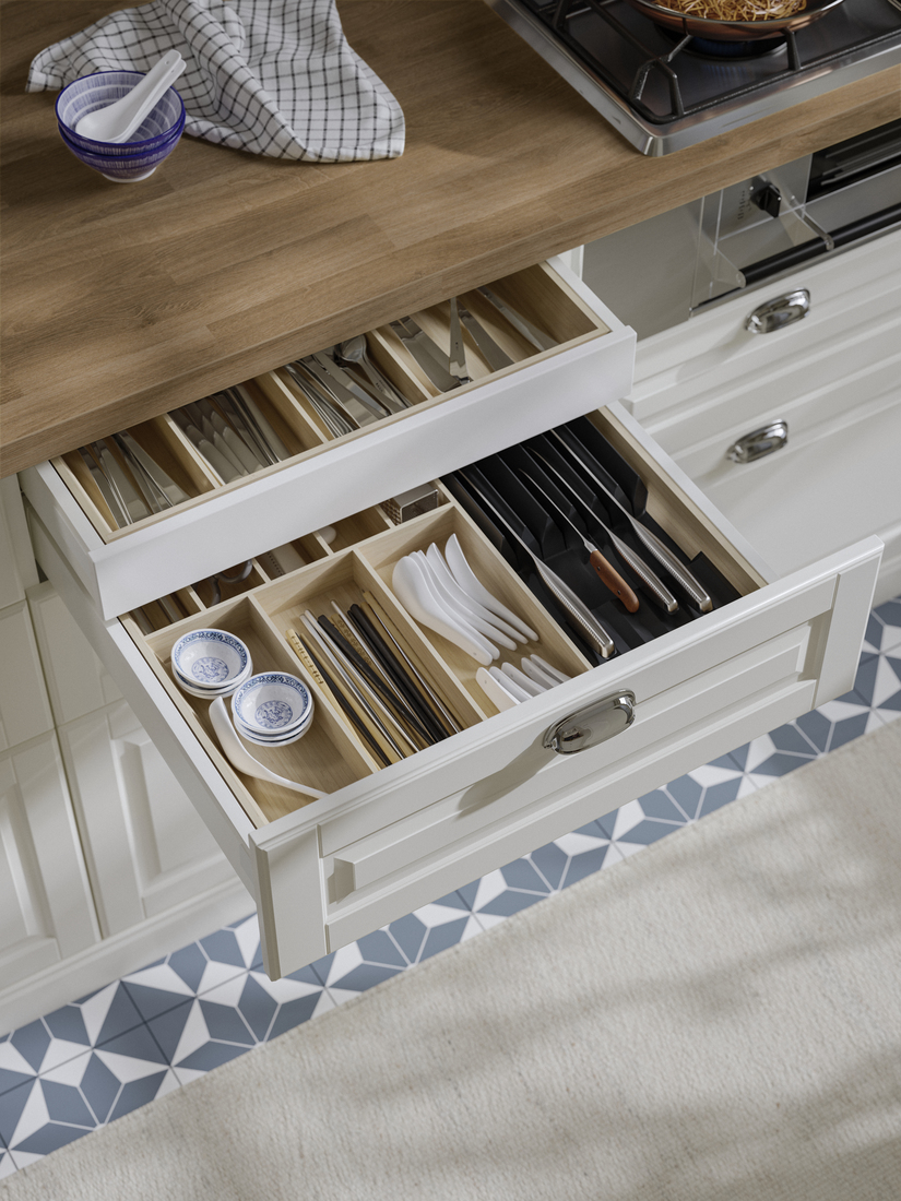 Sistema de estantería modular blanca de pared con ropa colgada en ganchos, suéteres doblados, un sombrero marrón y un bolso de cuero.