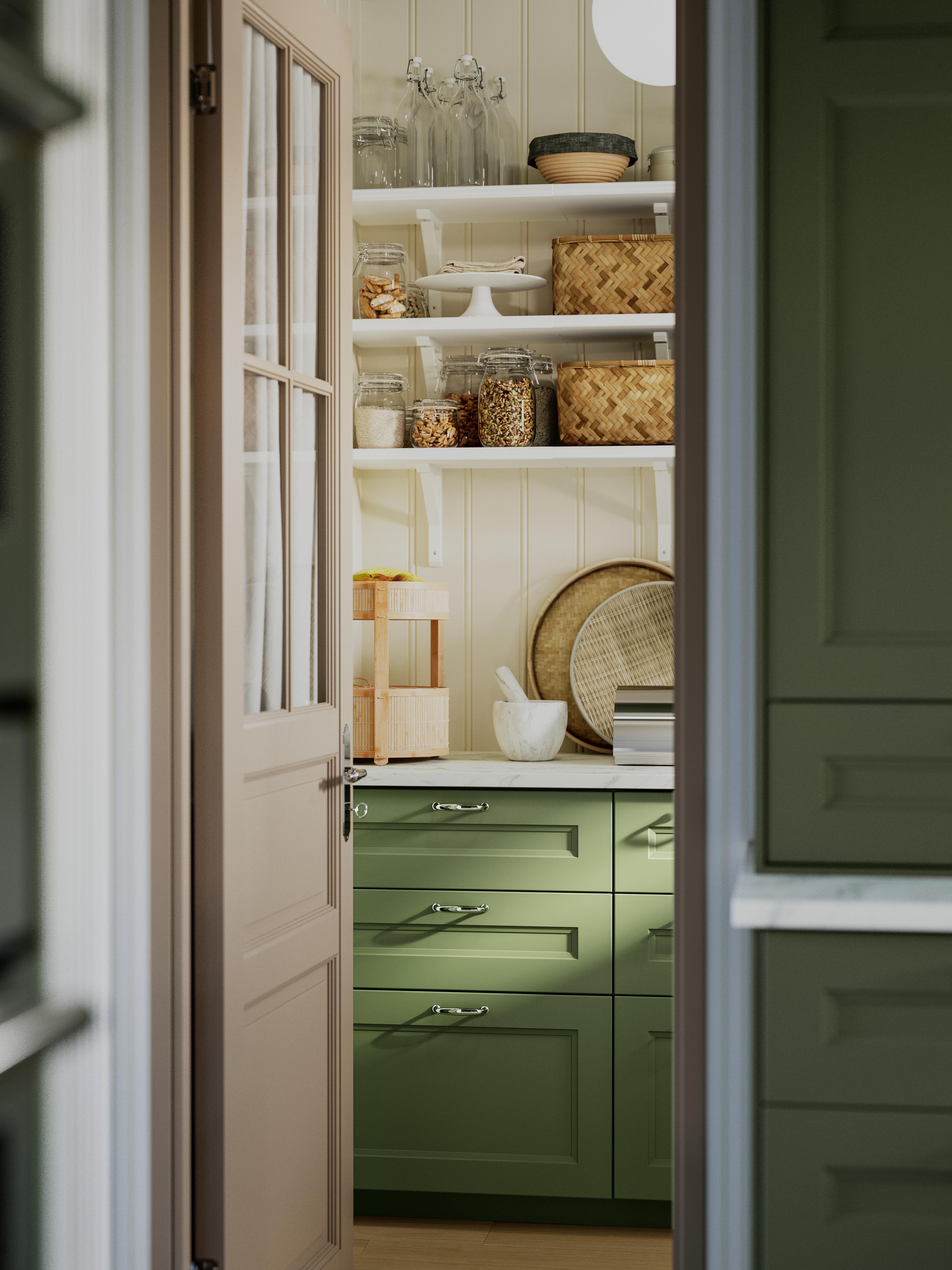 Organized pantry with shelves, glass jars, and green cabinets.