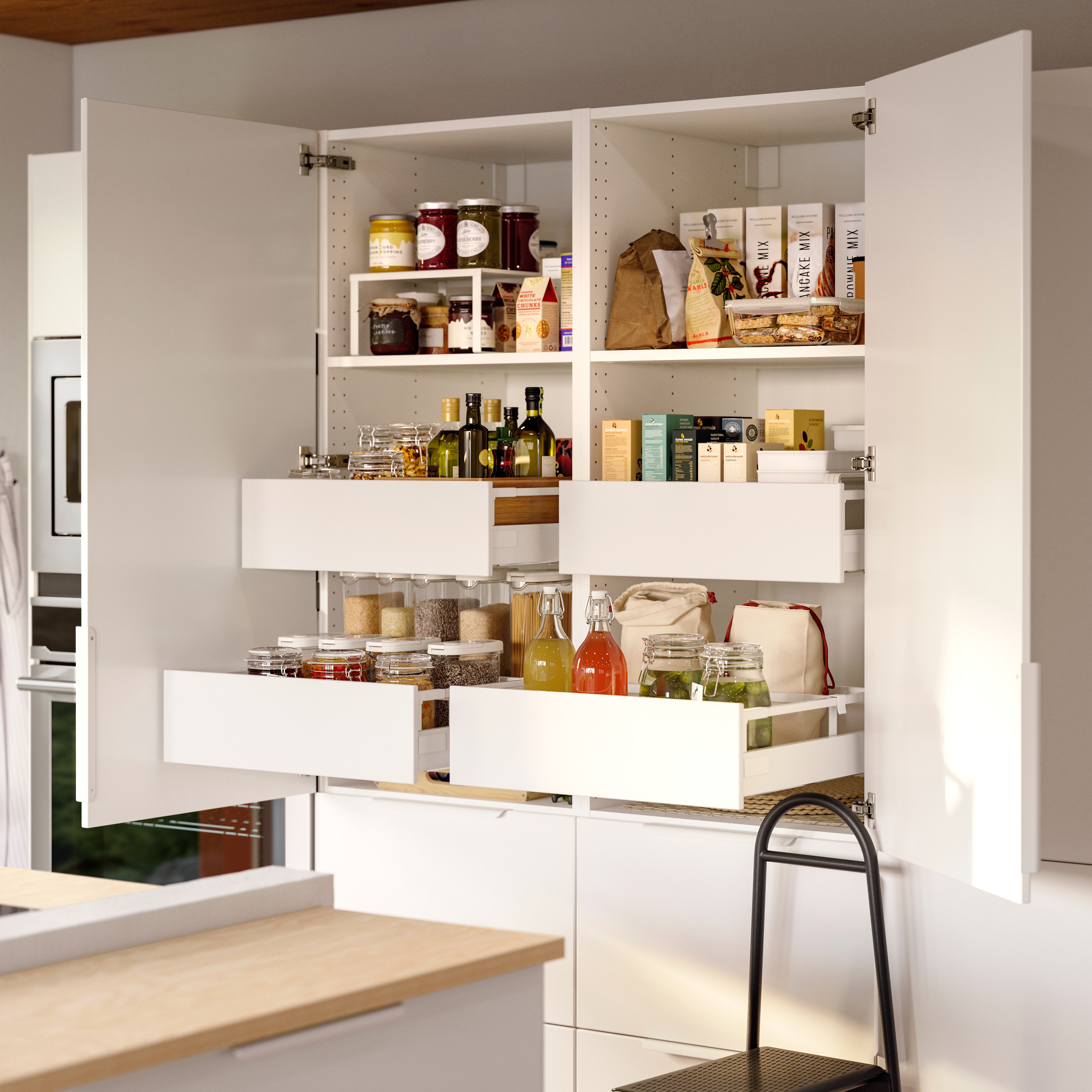 Open kitchen pantry cabinet with organized shelves and drawers holding food and jars.