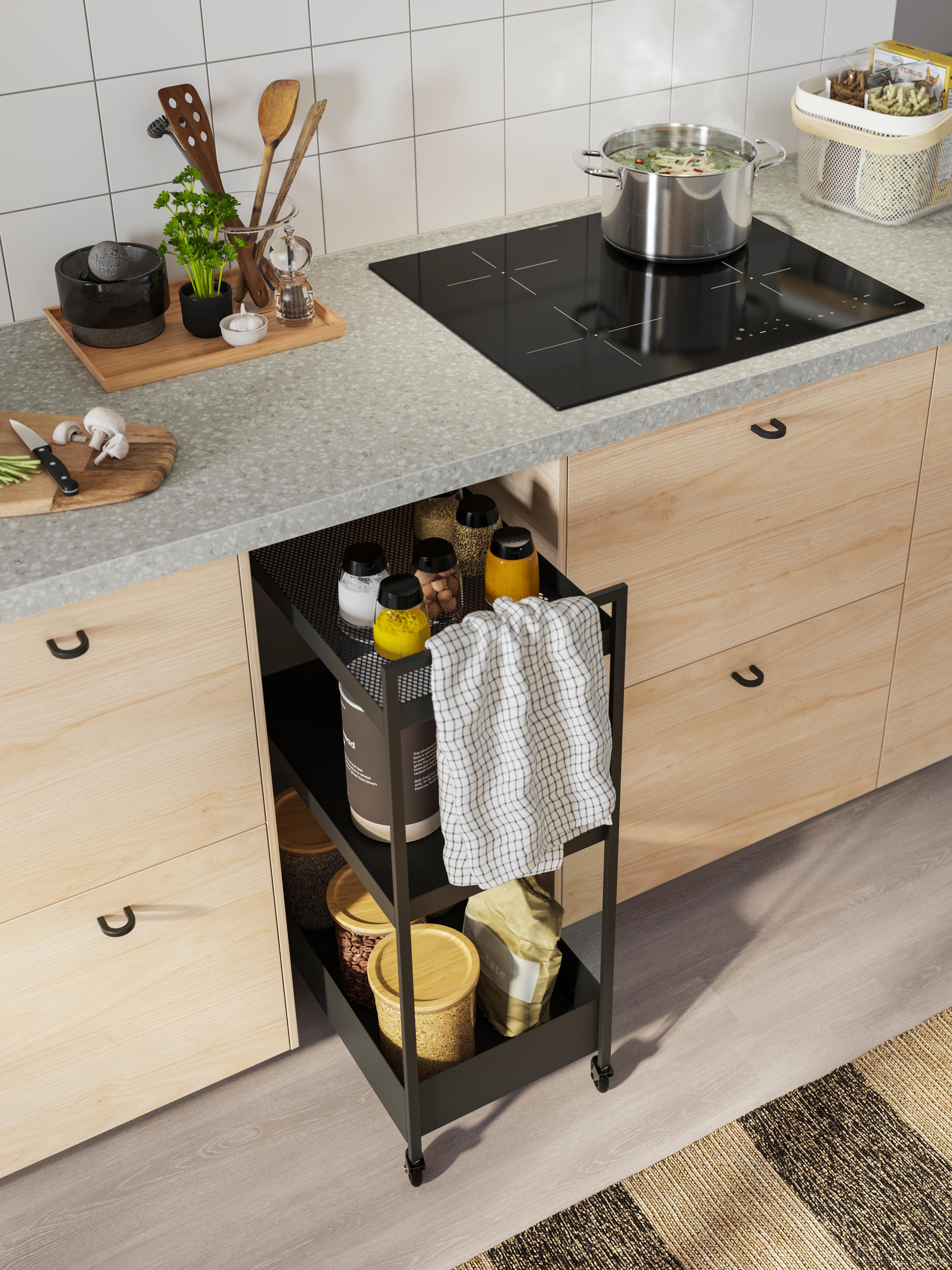 Slim rolling storage cart with spices and pantry items beside a modern kitchen counter.