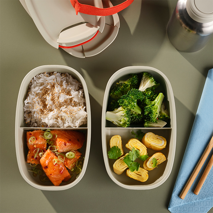 Recipientes bento preparados con arroz, salmón, brócoli y rollo de huevo.