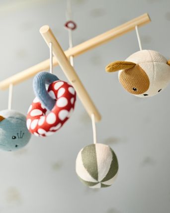 A GULLDVAVARE mobile with colourful and soft animals, rings and ballas is hanging from a ceiling.