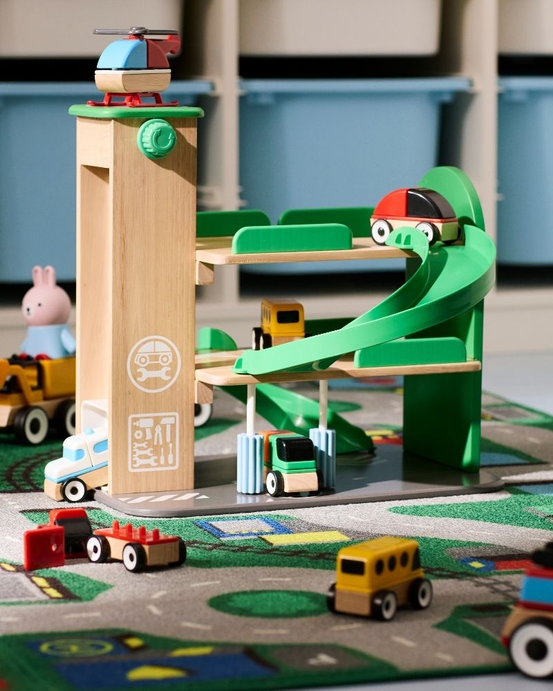 The complete LILLABO garage with helicopter and a lot of toy vehicles rolling around the garage, ramp and rug.