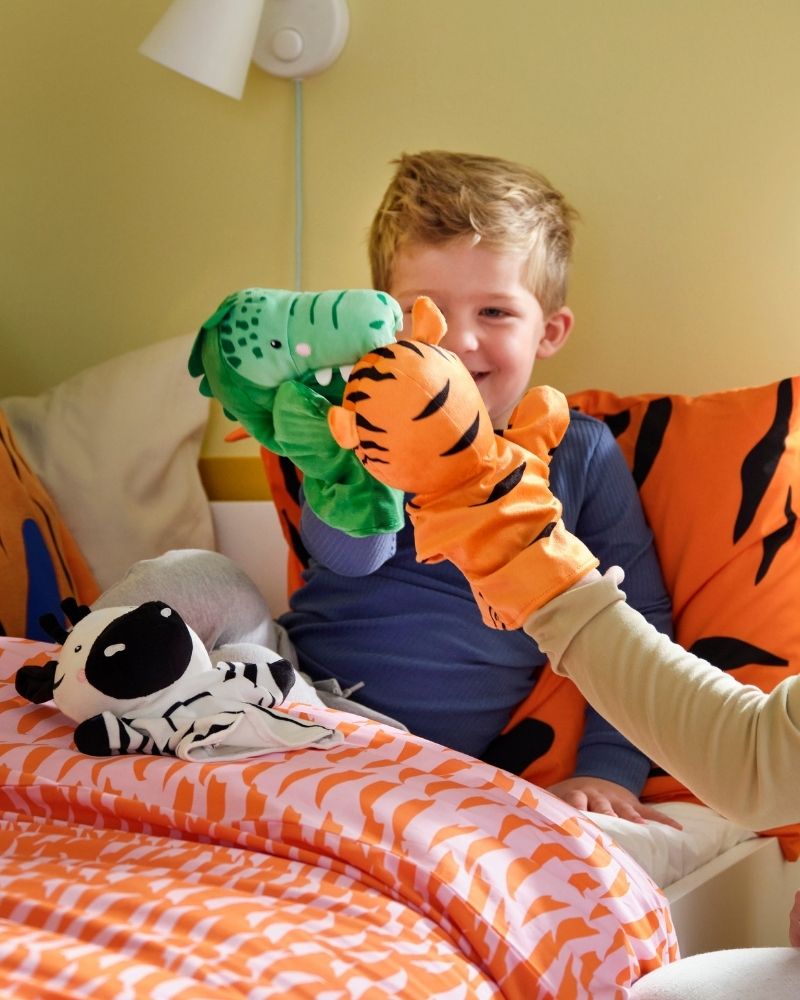 A child in bed and a woman are playing with NATTHÄGER hand puppets.