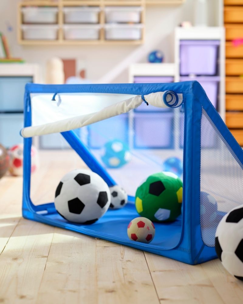 A blue SPORTSLIG ball goal and storage, full of SPARKA soft toy soccer balls.