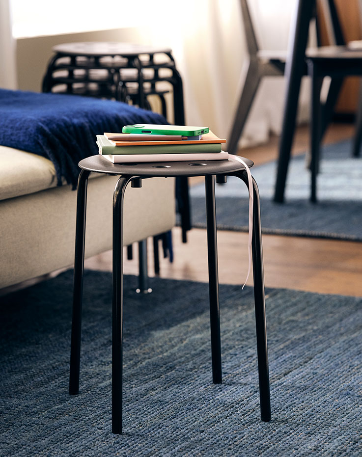 The Marius stool is in the foreground on a rug that serves as a centerpiece.