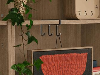 Mueble aparador de madera oscura con puertas cerradas y estantes abiertos con libros, cestas de fibra, plantas y florero.