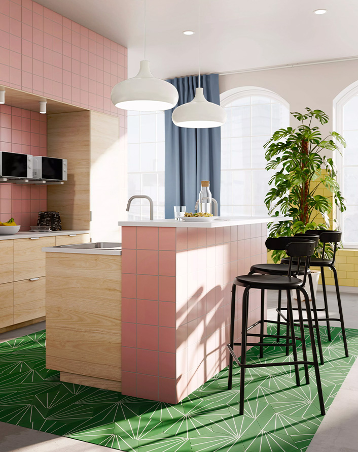 Modern kitchen with pink island, black bar stools, and decorative green flooring.
