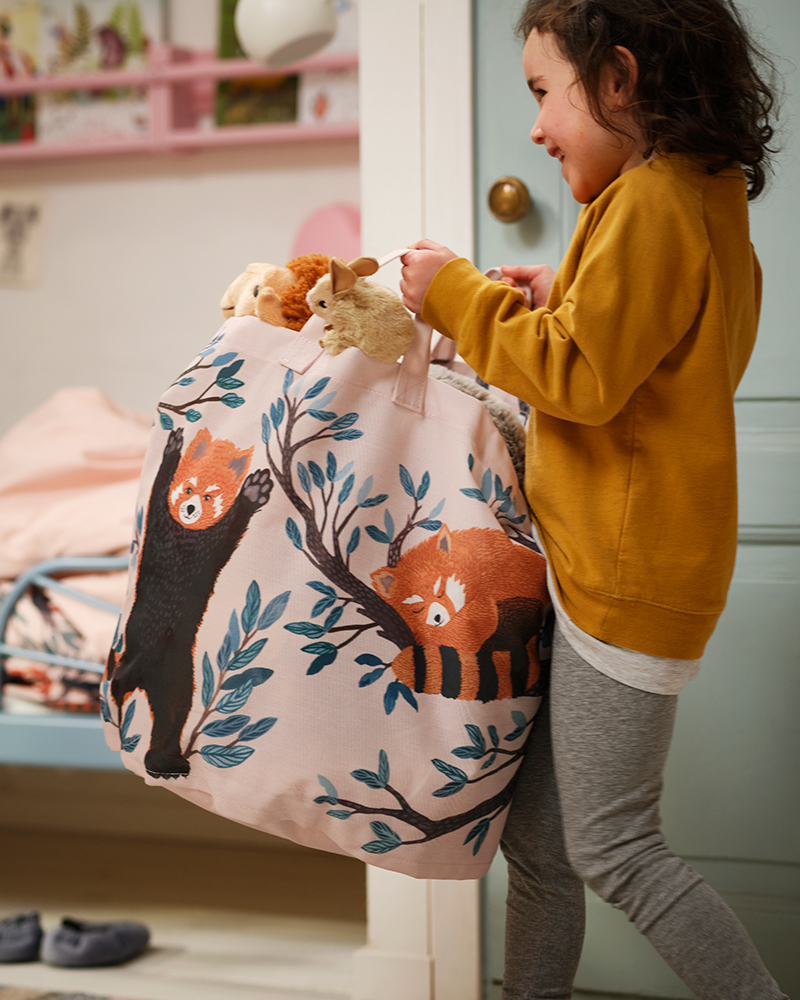 A child carrying an ALPTALL storage bag with a hand-painted design of red pandas.
