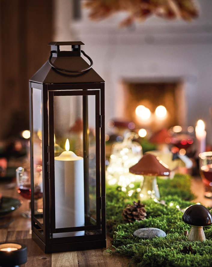 Lantern with a candle on a decorated table.