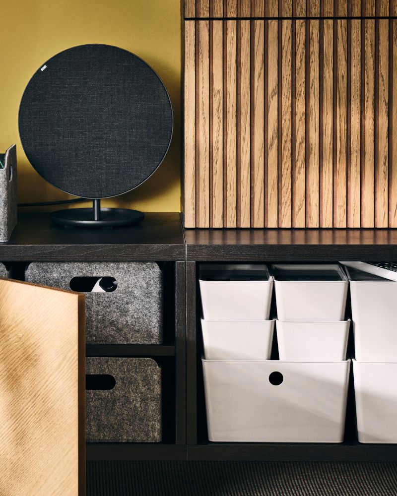 A wall-mounted BESTÅ storage combination, wood-veneer fronts open to reveal BESTÅ felt boxes and stacked white KUGGIS boxes.