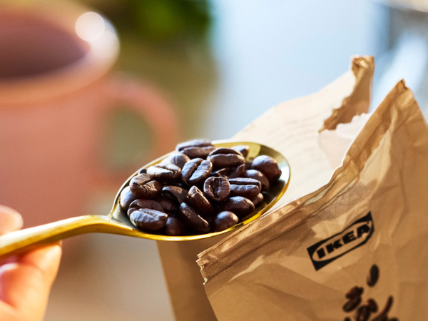 Golden spoon filled with coffee beans over an open IKEA bag.