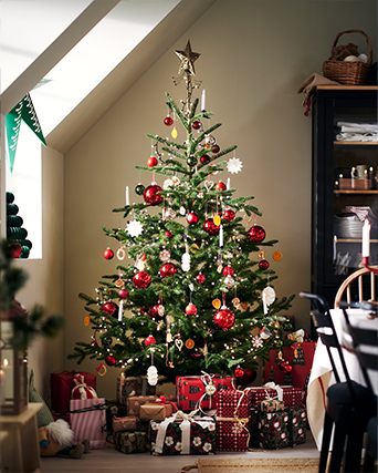 Decorative soft toys inspired by festive characters displayed among wrapped gifts in red and white patterns beside a Christmas tree.