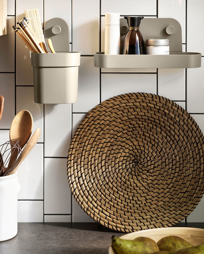 A section of kitchen wall fitted with an ÖBONÄS container with suction cups and an ÖBONÄS wall shelf with suction cups.