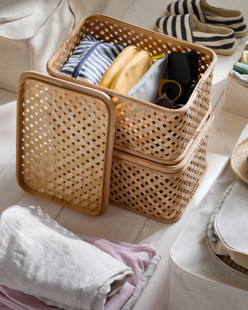 Woven storage basket with folded clothes placed on a bed in a tidy bedroom.