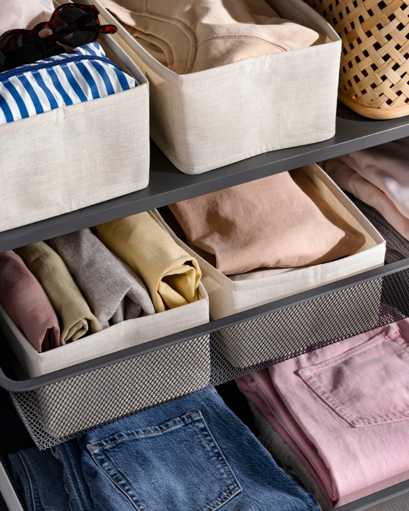 Fabric storage bins with neatly folded clothes arranged on shelves in an organized closet.