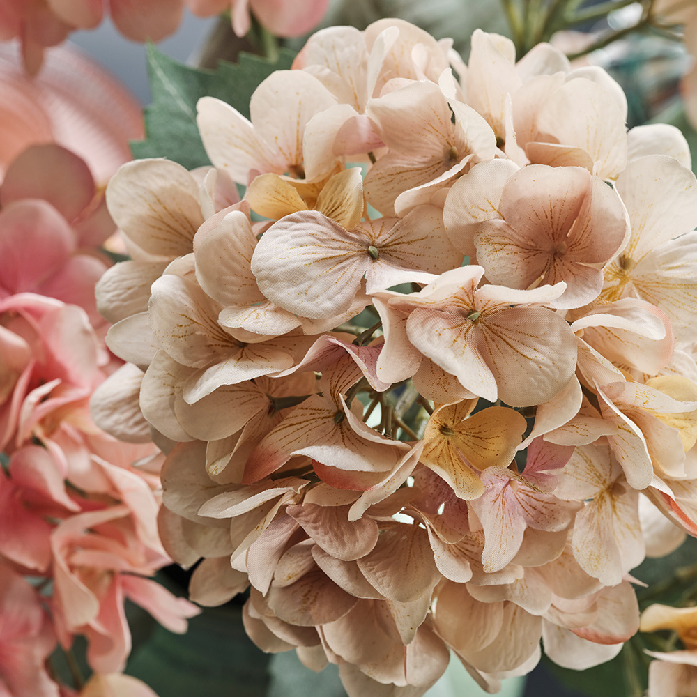 A close-up of a light beige SMYCKA artificial flower inspired by a hydrangea with its many small petals.