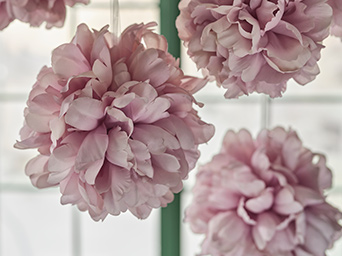 SMYCKA artificial flowers in pale pink are hanging from the ceiling in front of a window with a green frame.