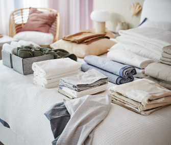 Ropa de cama y textiles doblados organizados sobre una cama.