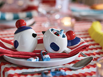 Bird-shaped ceramic containers on a plate set on a decorated table.