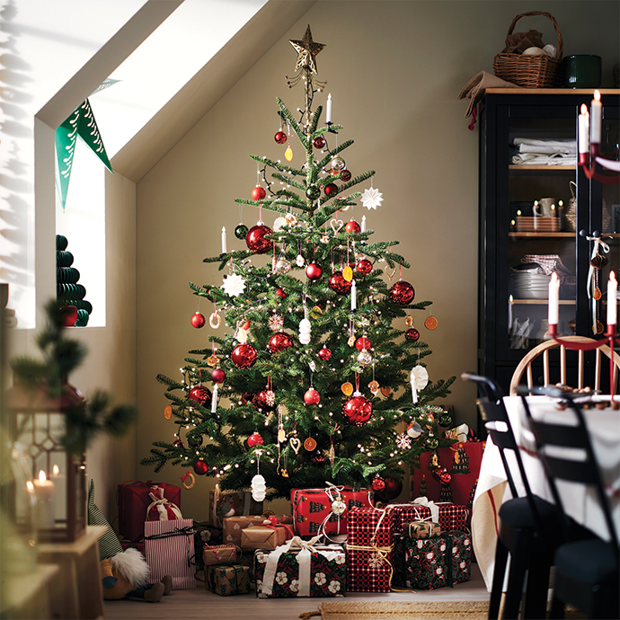 Decorated Christmas tree with red baubles and top star surrounded by presents.