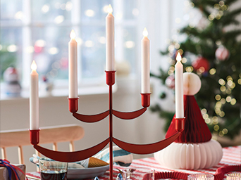 Red Christmas candelabra with white LED candles on a decorated table.
