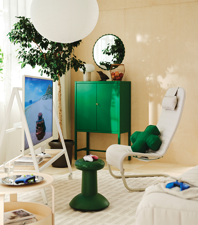 Modern living room with a white armchair, green cabinet, TV, and green cushion.