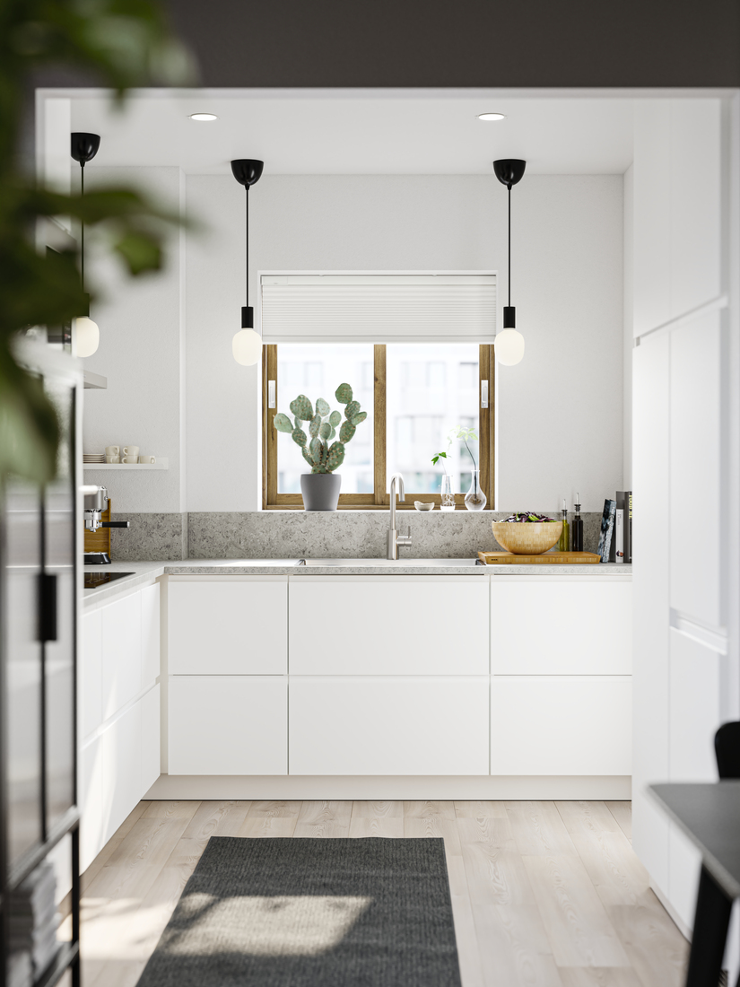 Cocina moderna blanca con ventana y cactus.