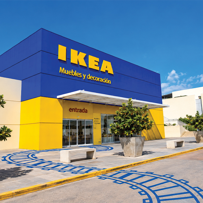 Exterior facade of a blue and yellow IKEA store with entrance and benches.