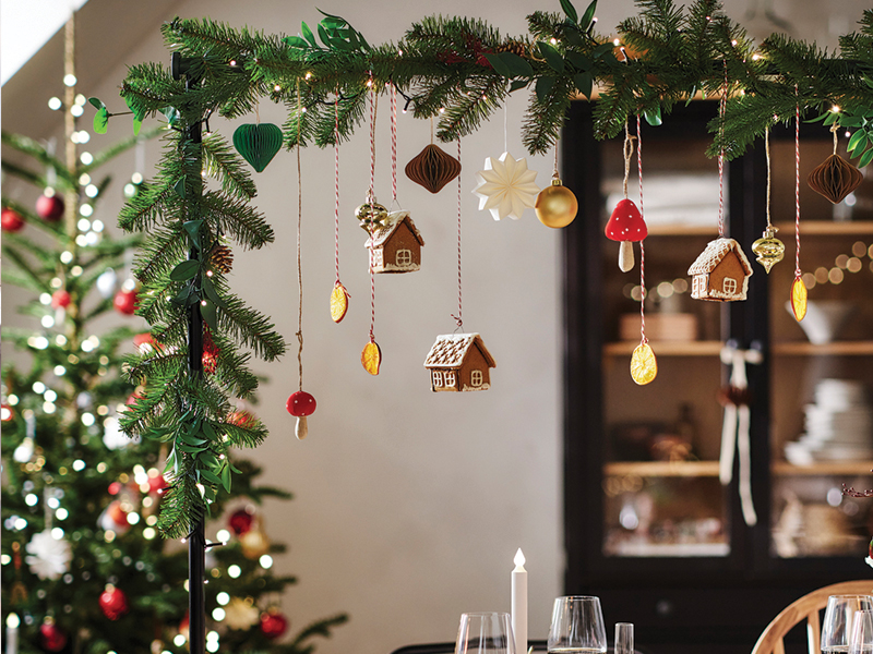Green Christmas garland decorated with small hanging house ornaments and figures.